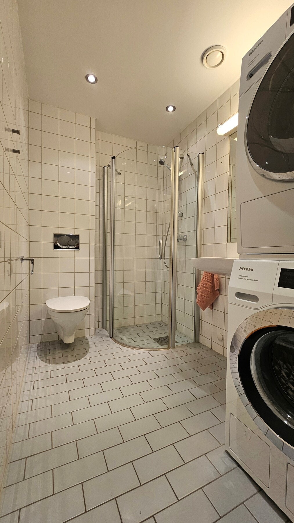 Flislagt baderom med servant, speil og belysning. Dusjløsning med nedsenket dusjsone. Vegghengt toalett og opplegg for vaskemaskin og tørketrommel. Galleribilde