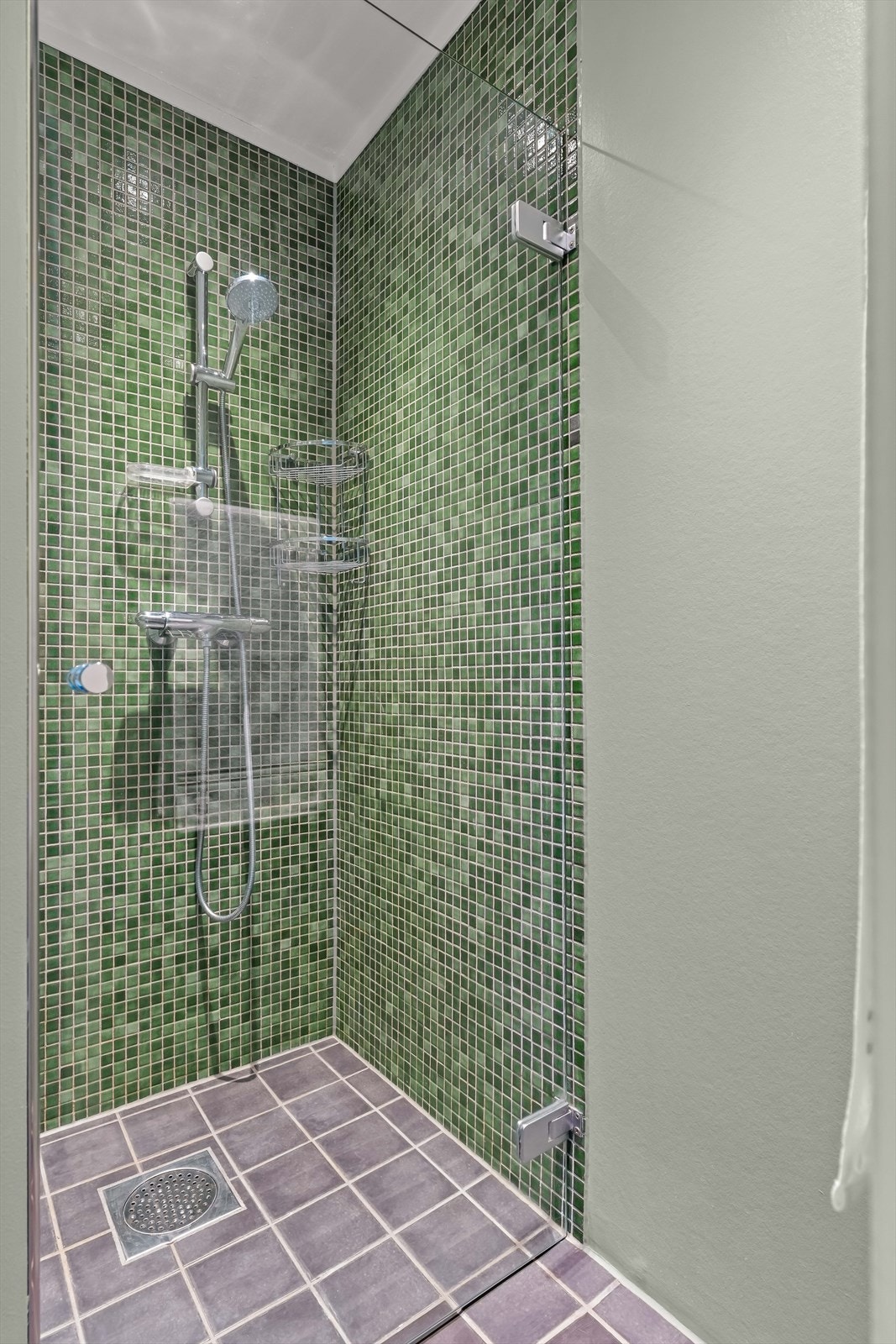 Stilrent dusjhjørne med svingbare dusjdører og vegghengt toalett. Et bad som kombinerer komfort og estetikk. Galleribilde