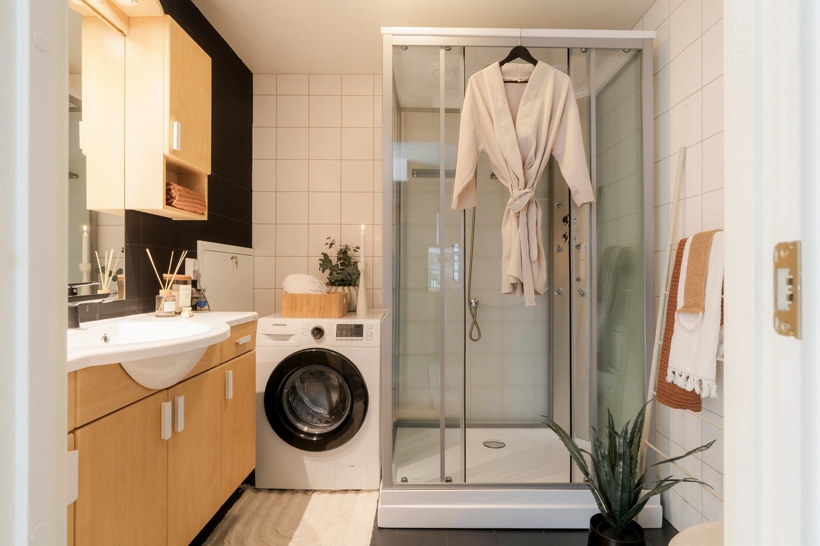 Badet er kompakt og godt utnyttet, med dusjkabinett, servant med underskap og opplegg for vaskemaskin. Galleribilde