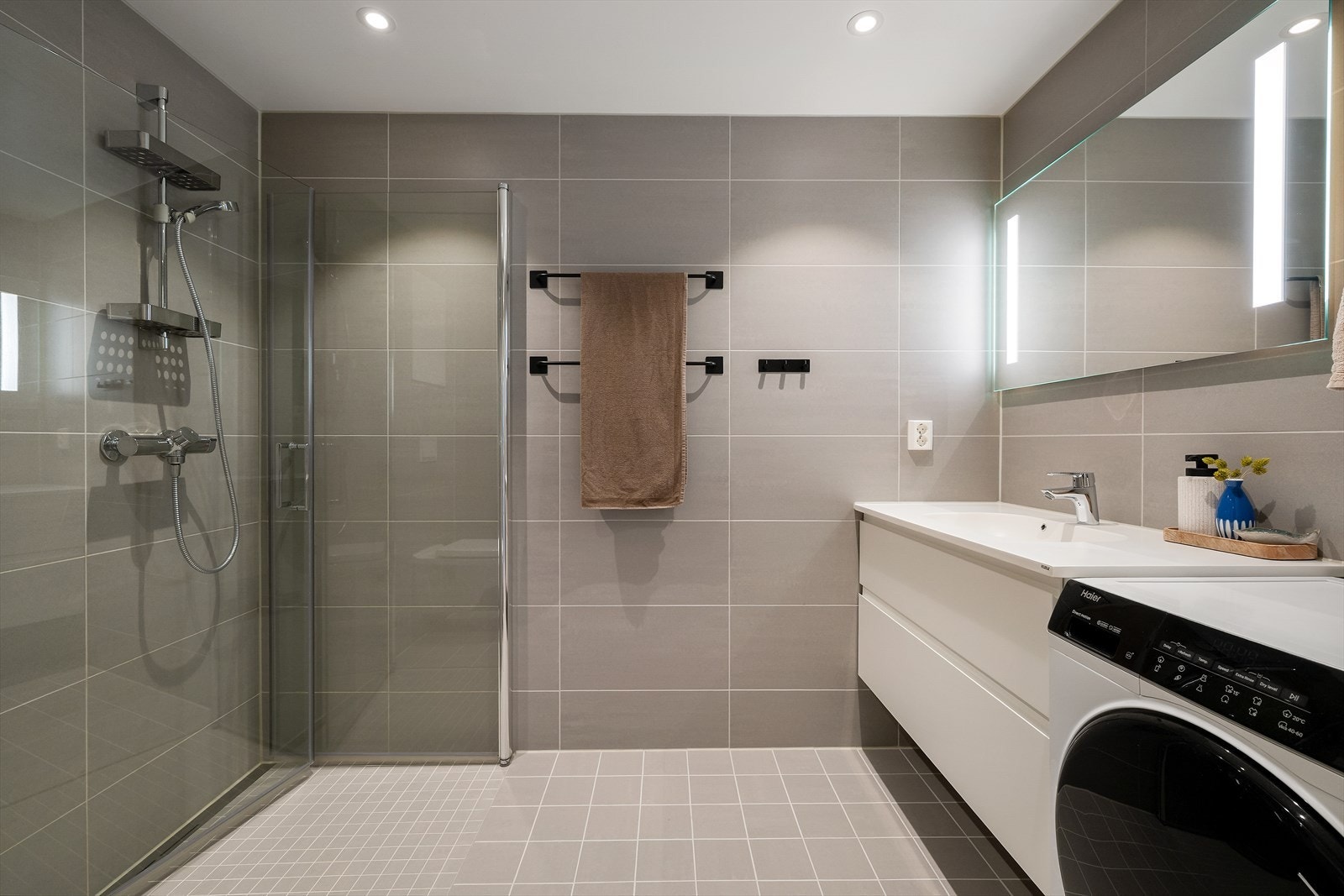 Delikat og moderne baderom med flislagte gulv, vegger og malt himling. Galleribilde