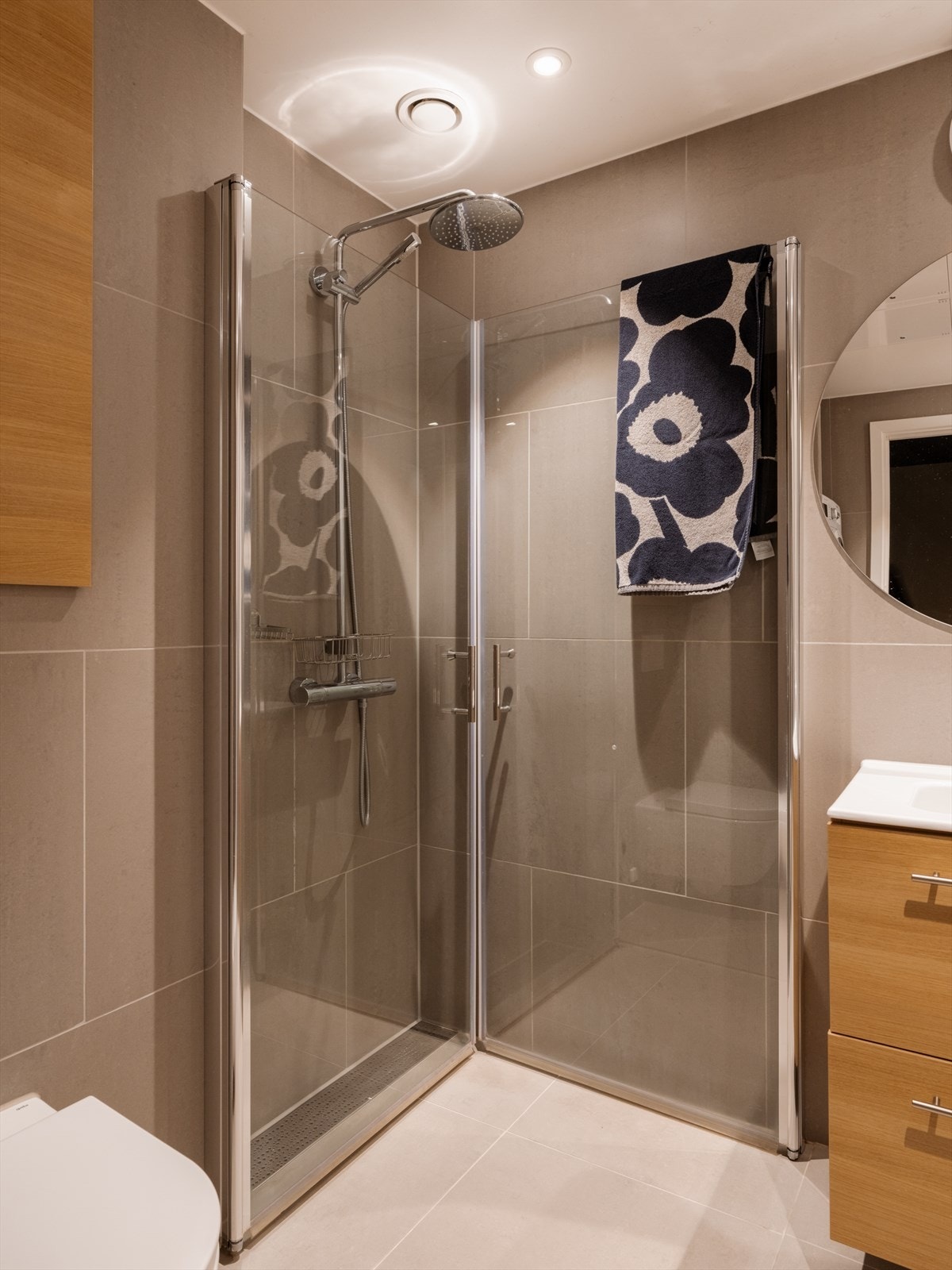 Badet består av servant innredning, vegghengt toalett og nedsenket dusj med glassdører Galleribilde