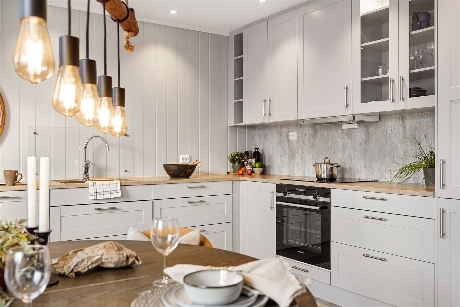 Kjøkkenet har grå profilerte fronter og laminert benkeplate med nedfelt oppvaskkum. Praktisk med glassplate i benkeryggen ved oppvaskkummen og plater i benkeryggen ved platetoppen. Galleribilde