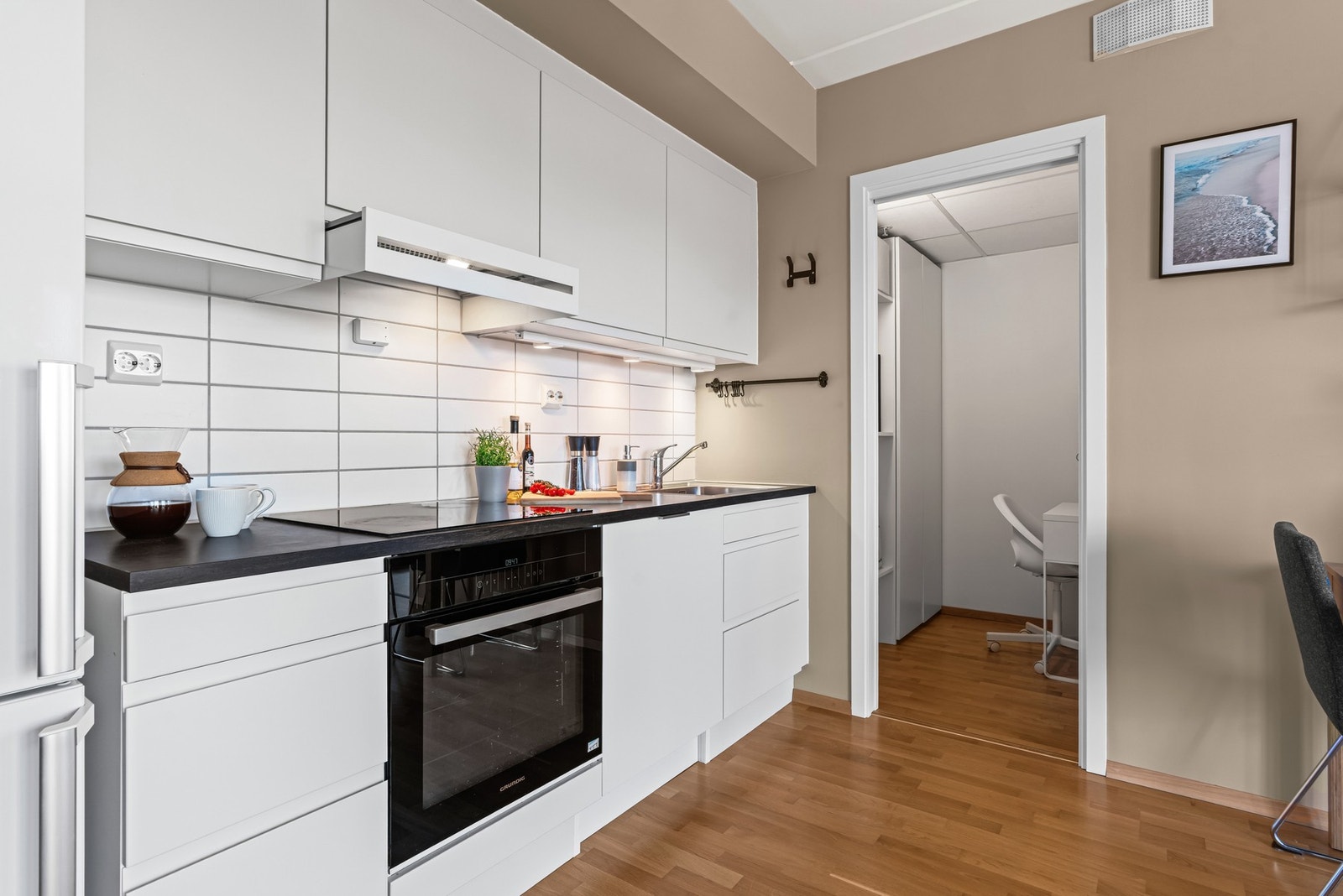 Kjøkkenet har hvite, glatte fronter og benkeplate av laminat. Galleribilde