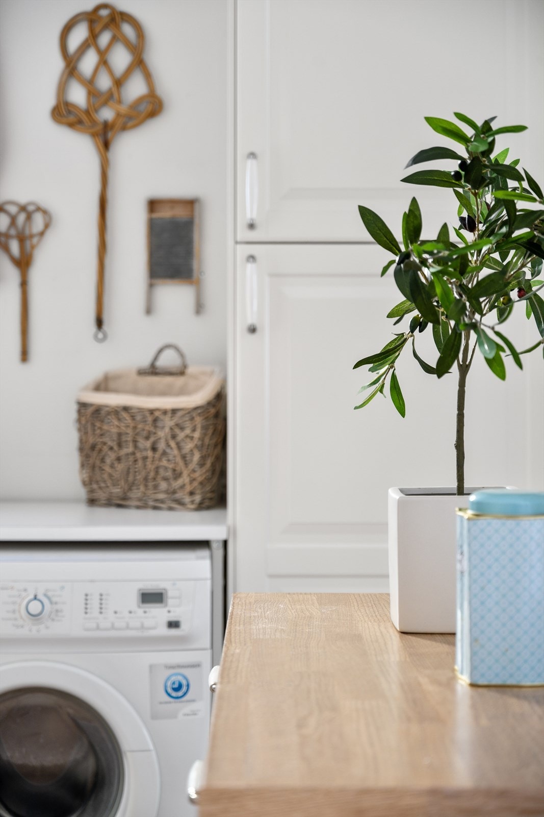 Da og nå: Et nostalgisk glimt fra vaskerommet - gamle teppebankere og et klassisk vaskebrett står stille i kroken, og minner om tidløs husholdningshåndverk midt i dagens praktiske vaskeløsning. Galleribilde