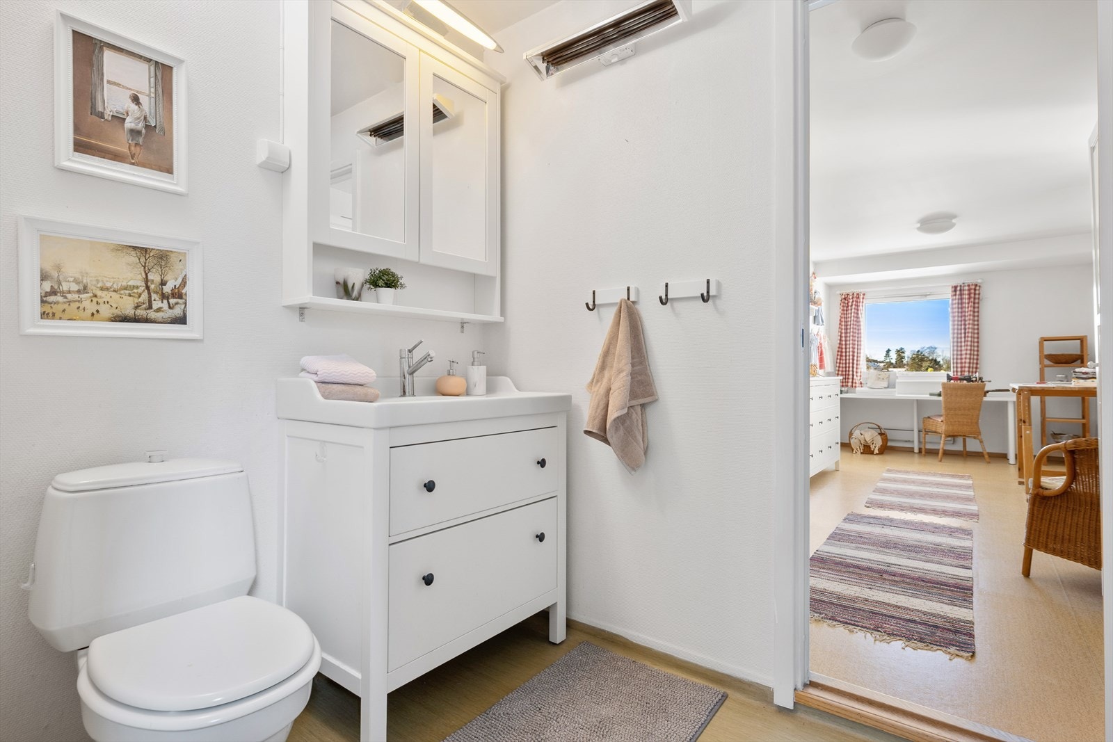 Easy access: Baderommet er lyst og funksjonelt med en gjennomtenkt planløsning. Her finner du stående klosett, praktisk servant på hvit baderomskommode med skuffer for god oppbevaring, og et speilskap med belysning som gir både lys og funksjon. Galleribilde