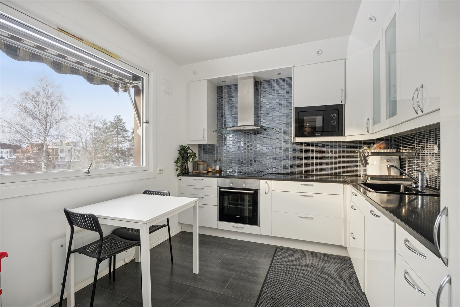 Kjøkkeninnredning med benke-og overskap med slette fronter, benkeplate av laminat og fliser på vegg over benk. Galleribilde