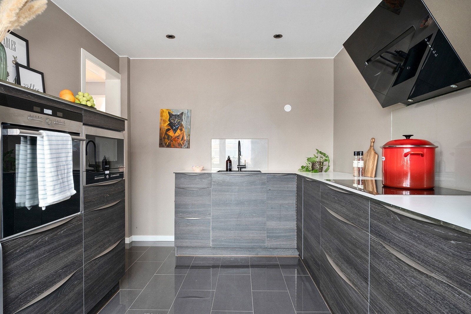 Kjøkkeninnredningen fra 2014 har en kompakt laminat benkeplate, glass over benk, kullfilter vifte og en limt kum. Galleribilde