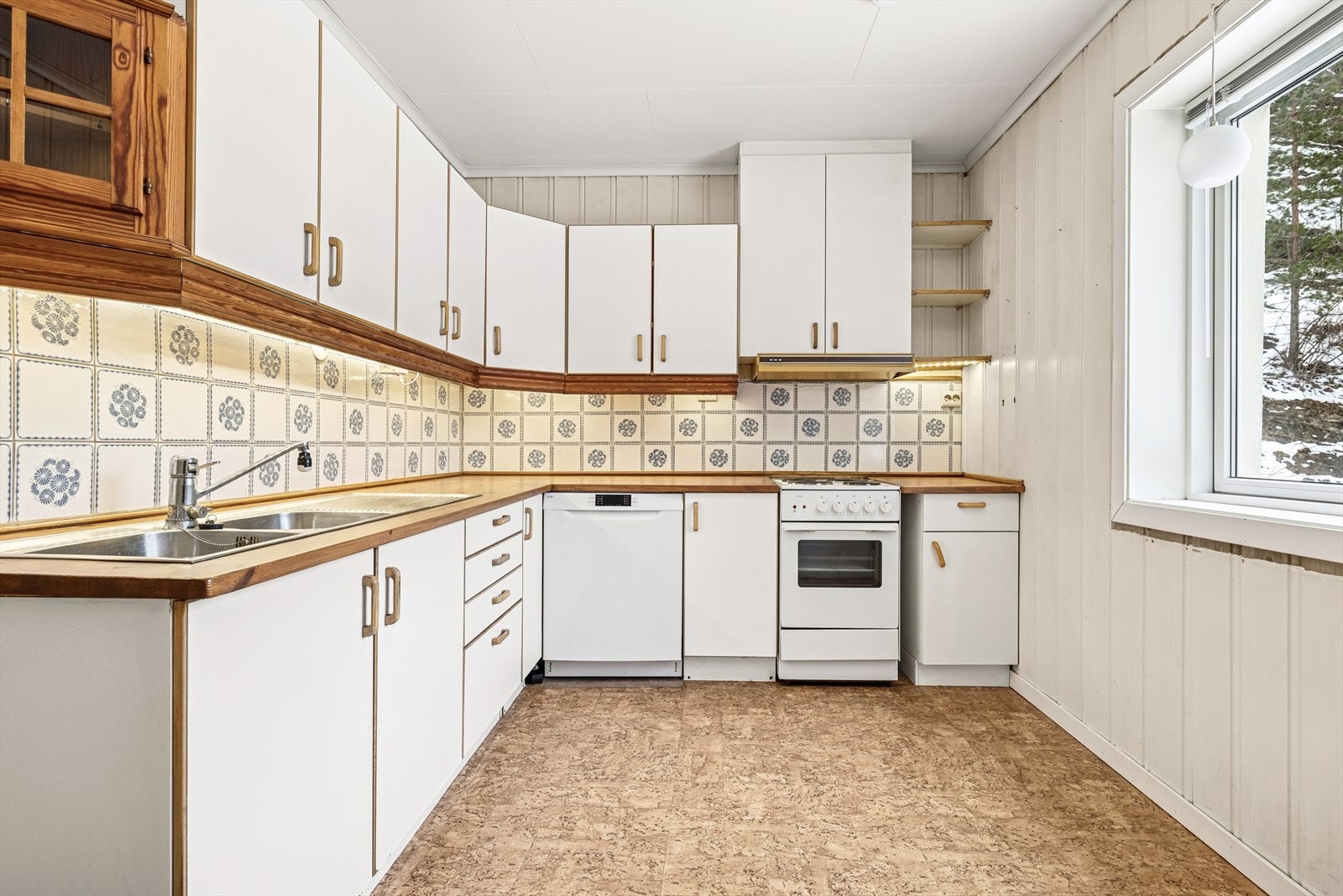 Praktisk vinkelkjøkken. Innredning med malte, glatte fronter og en solid benkeplate i heltre. Opplegg for oppvaskmaskin. Galleribilde