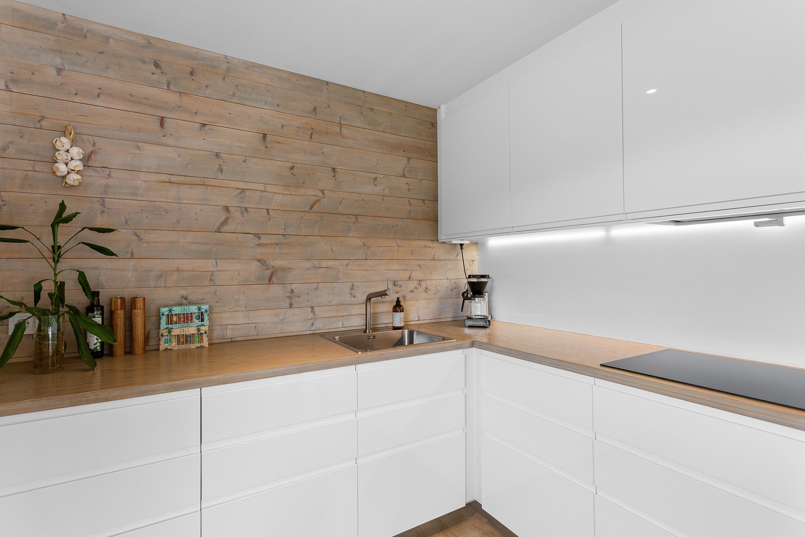 Glassplate montert mellom kjøkkenbenk og overskap. Benkeskapsbelysning over kjøkkenbenk. Galleribilde