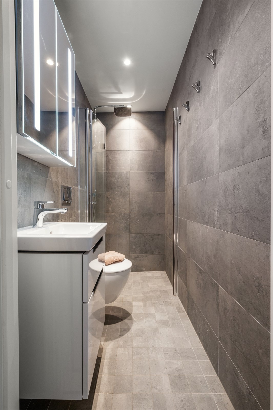 Bad 1: flislagt baderom med innfelt belysning i himlingen og servantinnredning med praktiske skuffer. Galleribilde