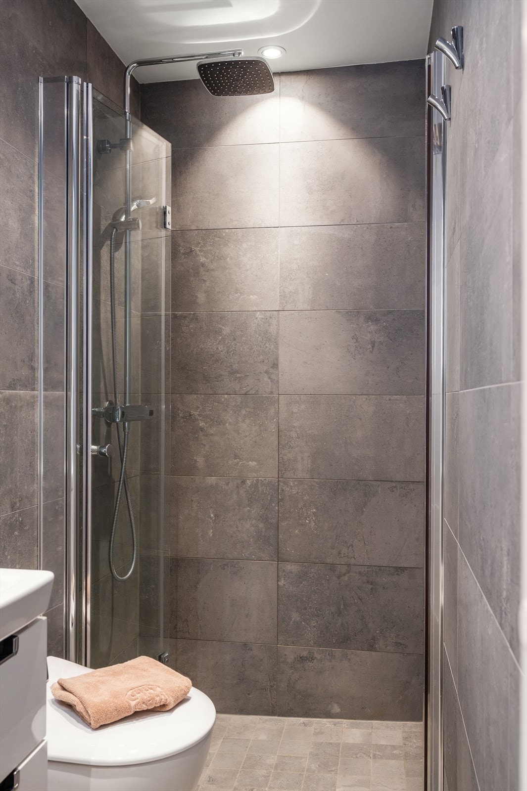 Bad 1 er innredet med vegghengt toalett og en dusjnisje med innfellbare dusjdører. Galleribilde