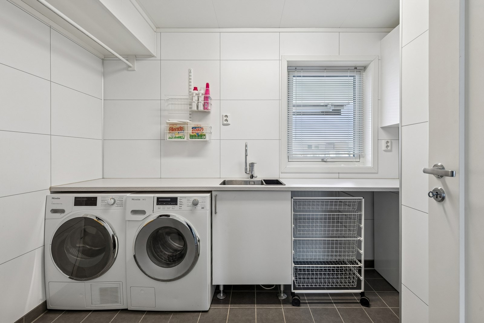 Vaskerom med innredning fra Sigdal. Her ligger alt til rette for praktisk og ryddig rom. En praktisk underlimt vask er også på plass. Rundt hjørnet er det et smart rom under trappen. Galleribilde