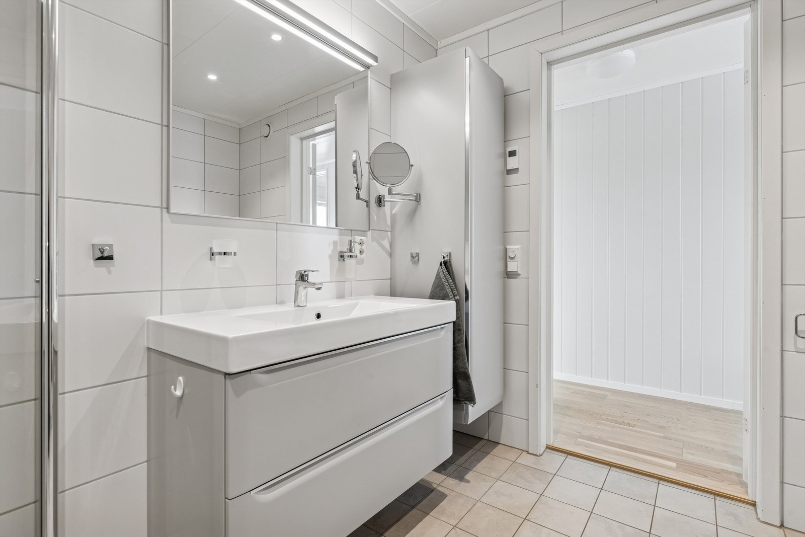 Baderomsinnredning med servantskap, overliggende servant og speil med belysning. Galleribilde