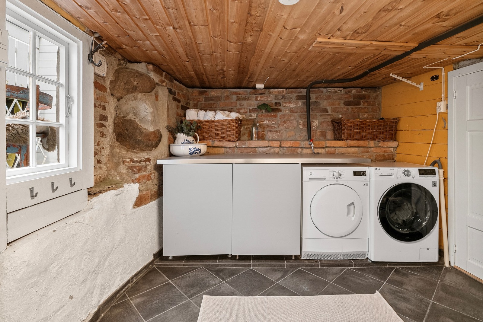 Vaskerommet ligger også i underetasjen og har flislagt gulv og rustikke teglvegger som gir rommet karakter. Galleribilde