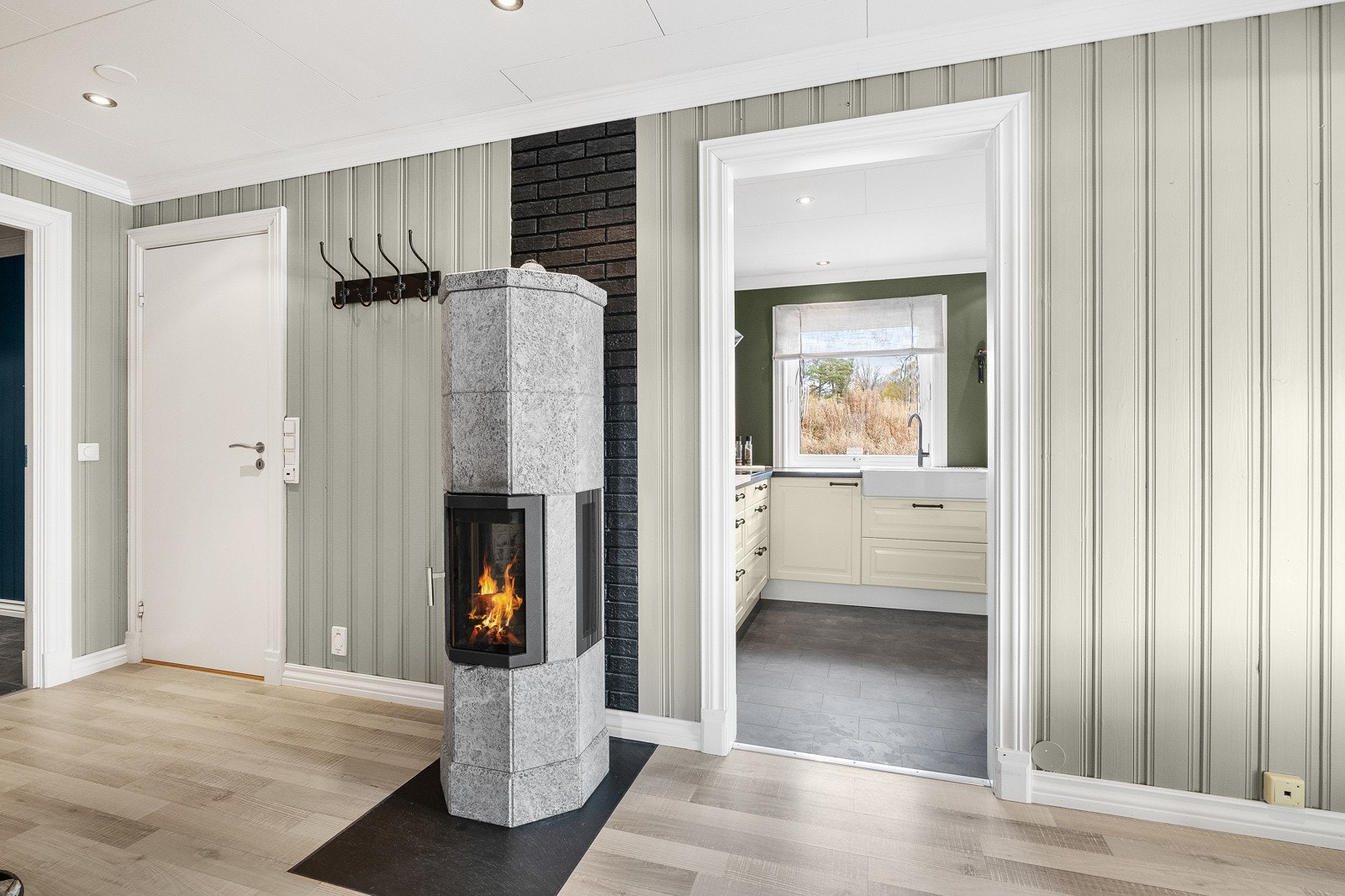 Lun sone mellom stue og kjøkken. Peisovn i kleberstein gir god varme og bidrar til en harmonisk romfølelse. Galleribilde