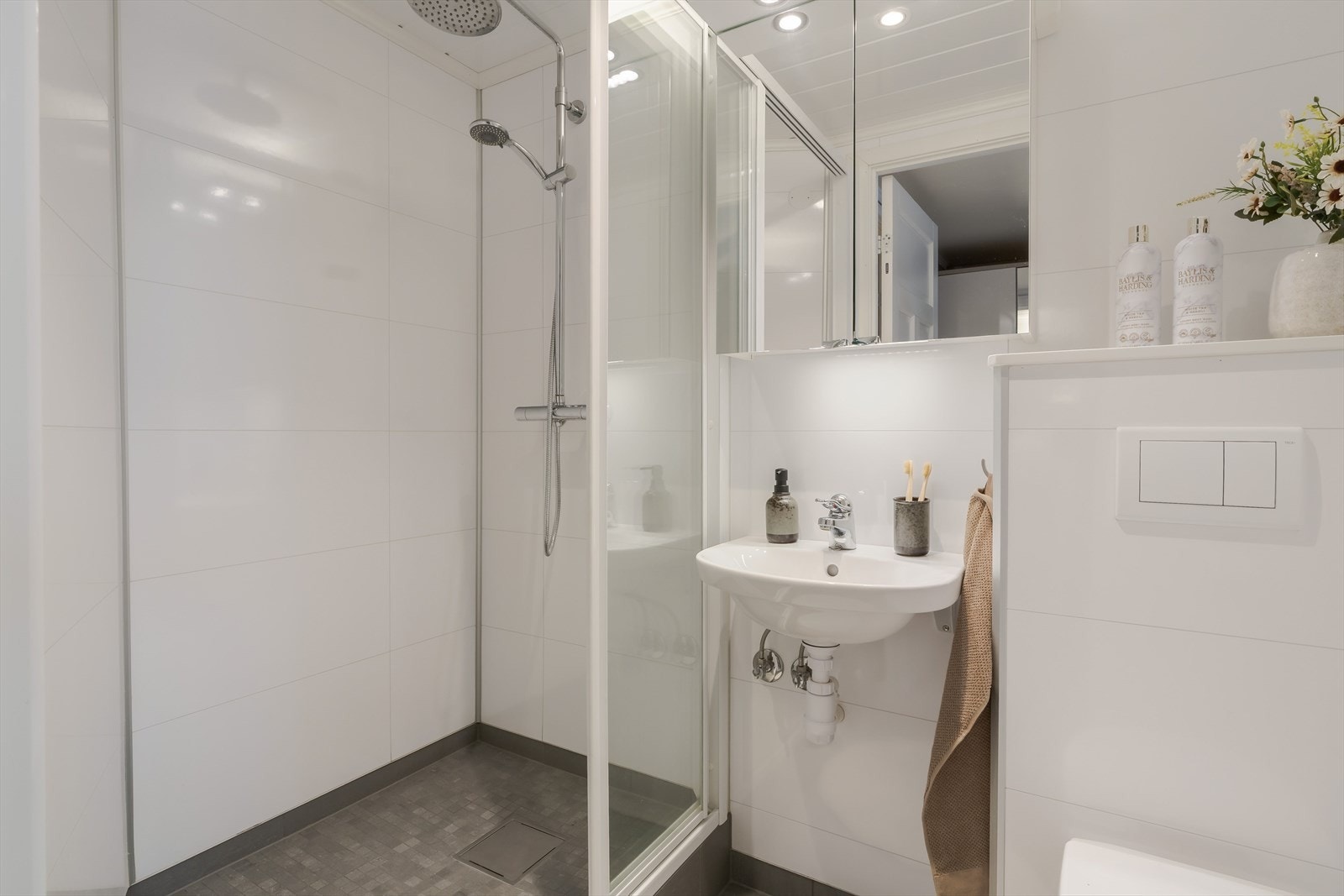 Badet har dusjhjørne med glassdører, servant med speilskap og vegghengt toalett. Galleribilde