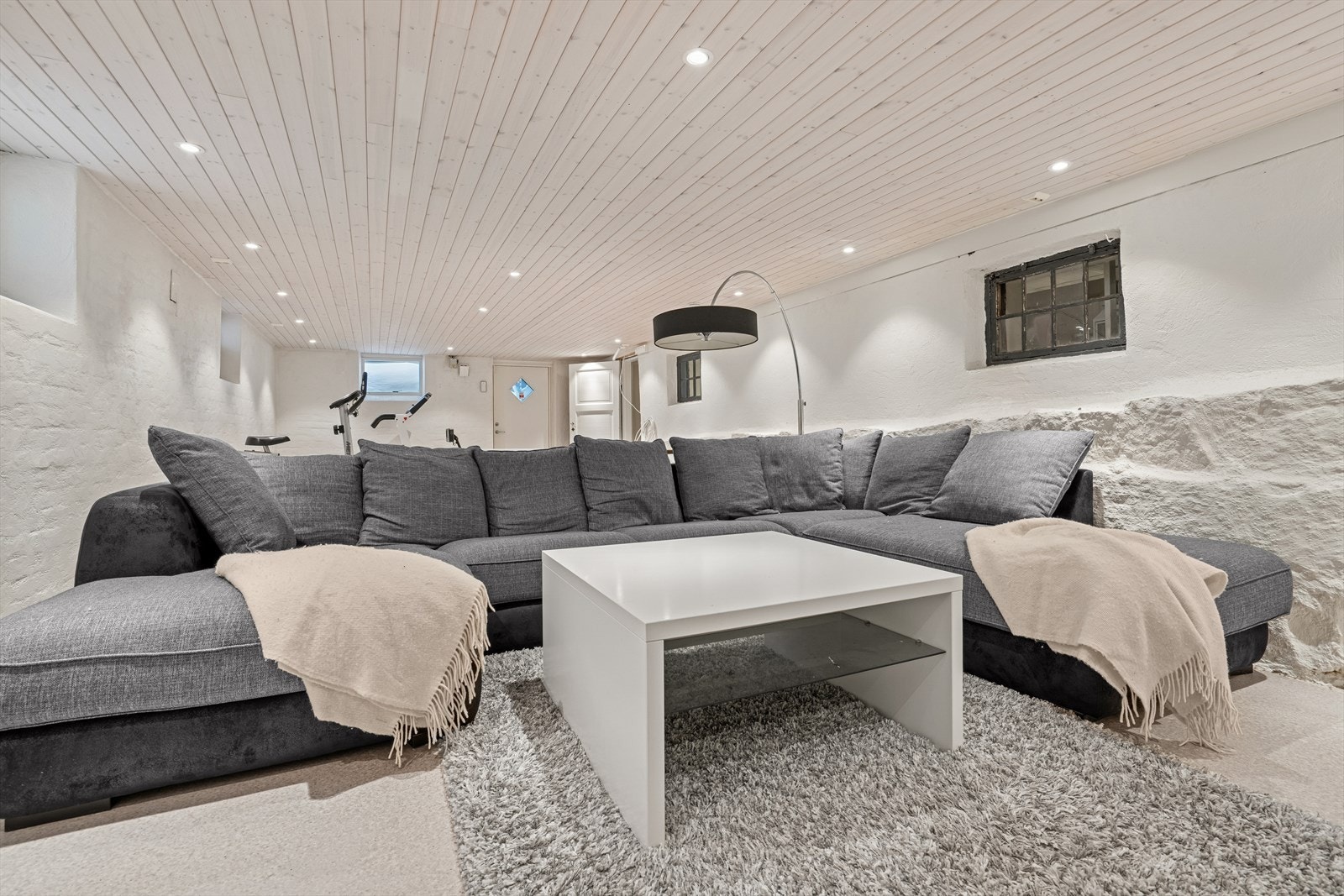 Rom innredet til kjellerstue/treningsrom har lyse overflater, downlights, vinduer og eget inngangsparti fra nordsiden av huset Galleribilde