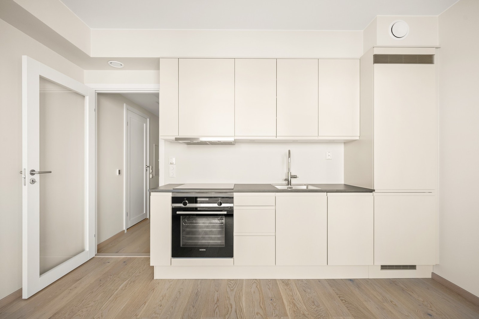 Kjøkkenet har moderne innredning fra Sigdal med slette fronter og integrerte hvitevarer fra Simens. Galleribilde