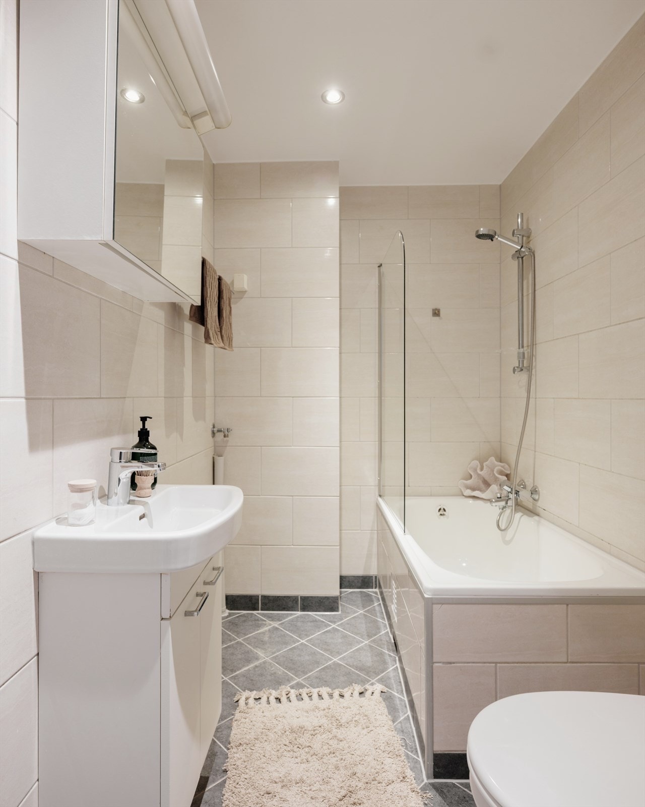 Badet er innredet med servant, toalett og badekar med dusj. Det er opplegg for vaskemaskin i hjørnet. Galleribilde