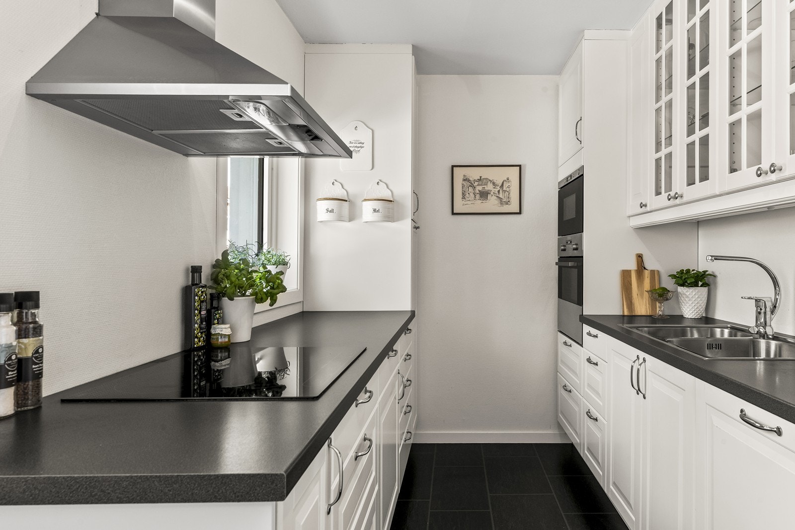 Plassbygd kjøkkeninnredning med profilerte fronter, integrerte hvitevarer og noen overskap med glassfronter Galleribilde