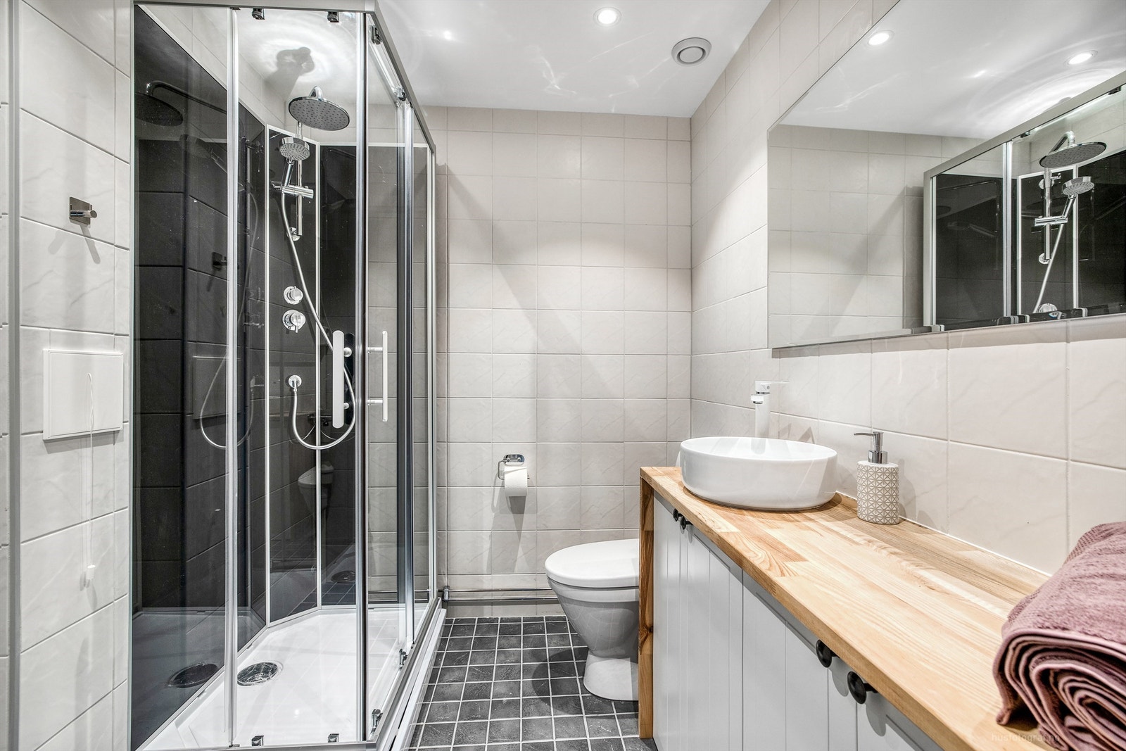 Et pent, flislagt bad med vegghengt toalett og downlights i taket. Galleribilde