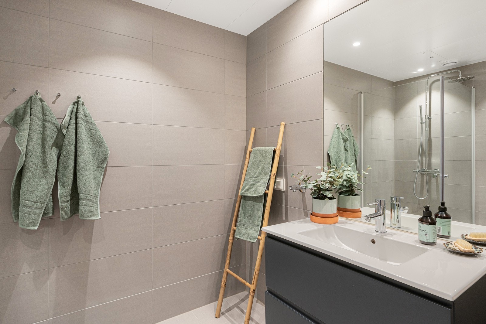 Servantinnredningen er vegghengt med skuffer og heldekkende servant. Til venstre for servant er det avsatt plass til vaskemaskin og tørketrommel i vaskesøyle. Galleribilde