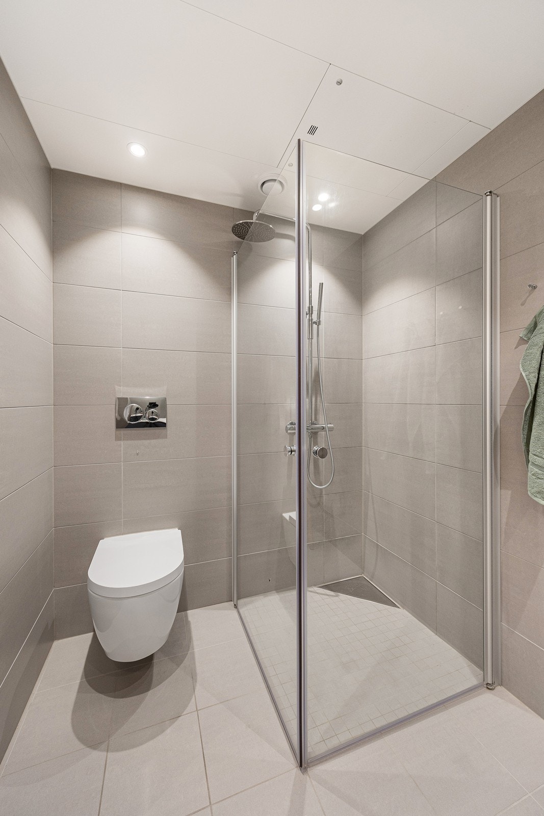 Rommet er innredet med vegghengt toalett, dusjhjørne med glassdører, dusjarmatur med en herlig regfallsdusj. Galleribilde