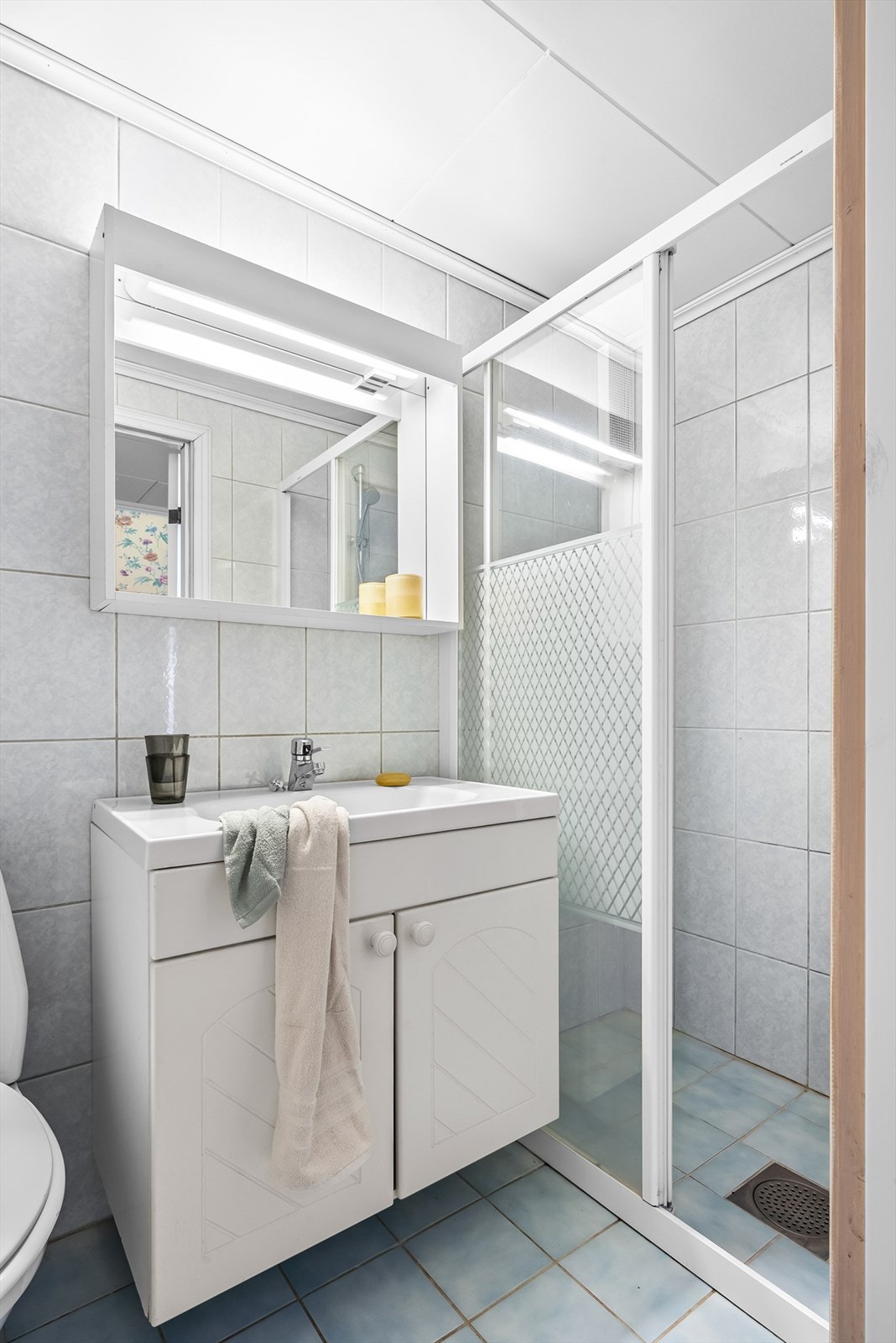 Flislagt bad med nedfelt servant, gulvstående toalett og dusj med håndholdt dusjmatur. Det er installert elektriske varmekabler i gulvet Galleribilde