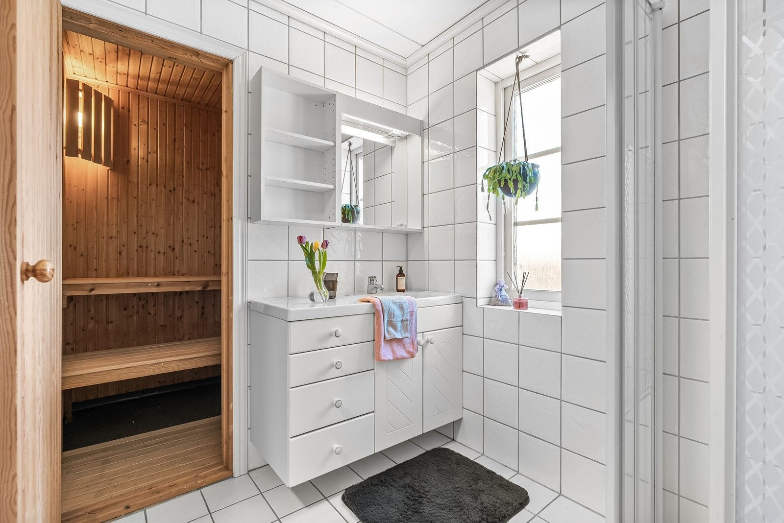 Badet fra byggeår med direkte adkomst til badstue. Overflatene på vegger og gulv er flislagt, mens taket er malt. Badet er innredet med en nedfelt servant og overhengende speil Galleribilde