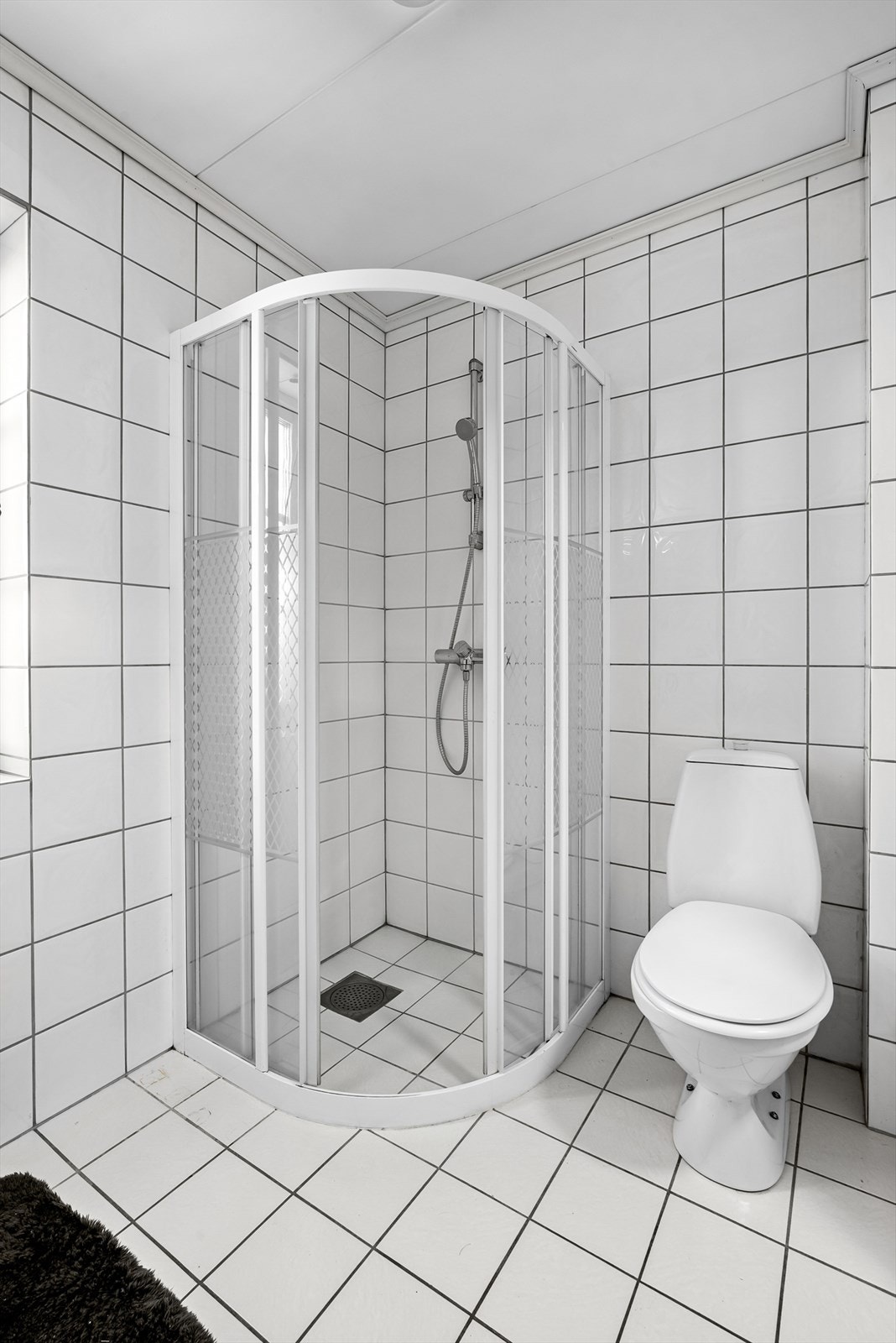 Dusjen er plassert i hjørnet og har håndholdt dusjarmatur. Det er installert elektriske varmekabler på gulv Galleribilde