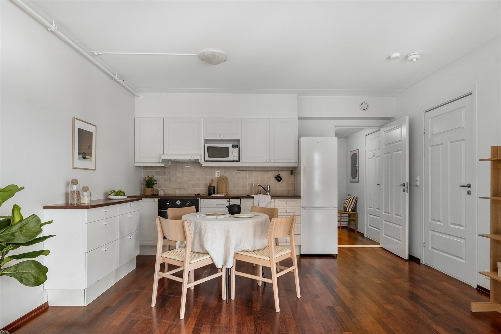 Kjøkkeninnredningen har et klassisk uttrykk med profilerte og glatte fabrikklakkerte fronter, belysning under overskap, flislagt bakvegg, benkeplate i laminat og nedfelt kum. Galleribilde