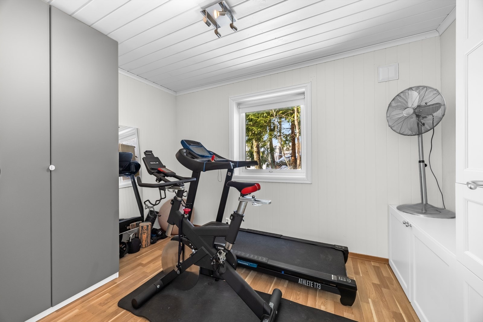 Romslig og pent soverom i boligens 1. etasje som benyttes som trimrom. Her er det god plass til seng med tilhørende nattbord. Det er montert et romslig garderobeskap og annen skapinnredning. Galleribilde