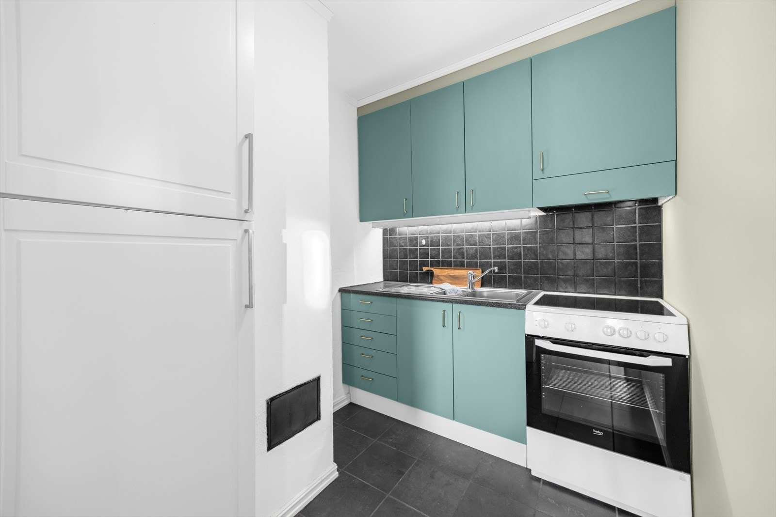 Kjøkkenet er utstyrt med glatte, malte fronter, benkeplate i laminat, rustfri oppvaskkum med avrenningsplate og ventilator. Feieluke til pipe. Galleribilde