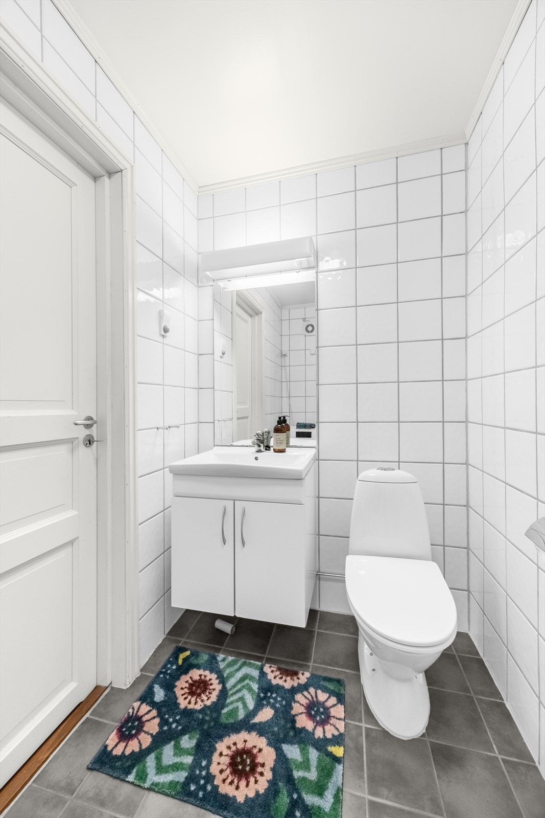 Flislagt bad med vannbåren gulvvarme. Rommet inneholder veggmonterte dusjvegger, dusj direkte på gulv med termostat batteri, klosett, servant med skapinnredning, speil og belysning. Galleribilde