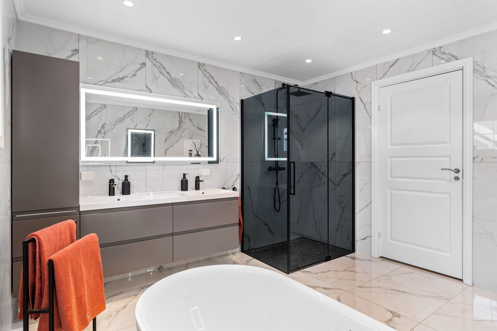 Rommet er utstyrt med baderomsinnredning, dobbel servant, servantskap, servant, veggmontert wc og dusjhjørne med innfellbare dører og badekar. Galleribilde