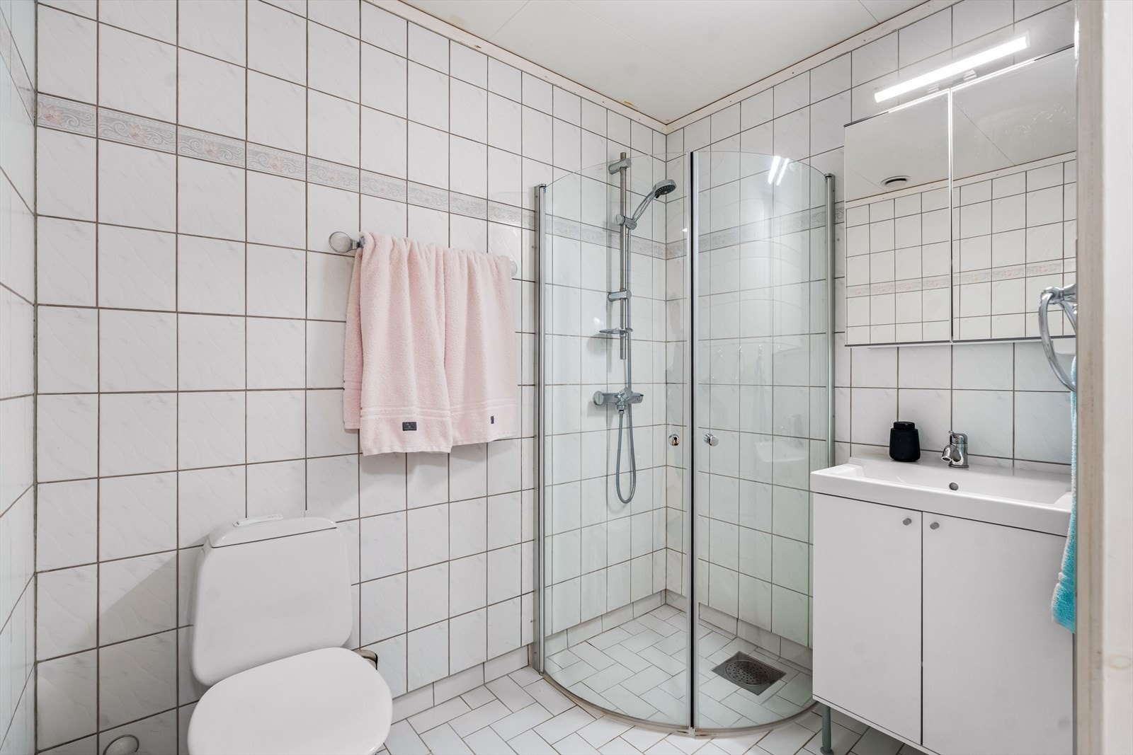 Baderommet i kjelleren har flislagte gulv- og veggflater, samt takess i himling. Rommet har servant, servantskap, speilskap, wc og dusjhjørne med innfellbare dører. Baderommet får TG2 av takstmann grunnet alder. Galleribilde