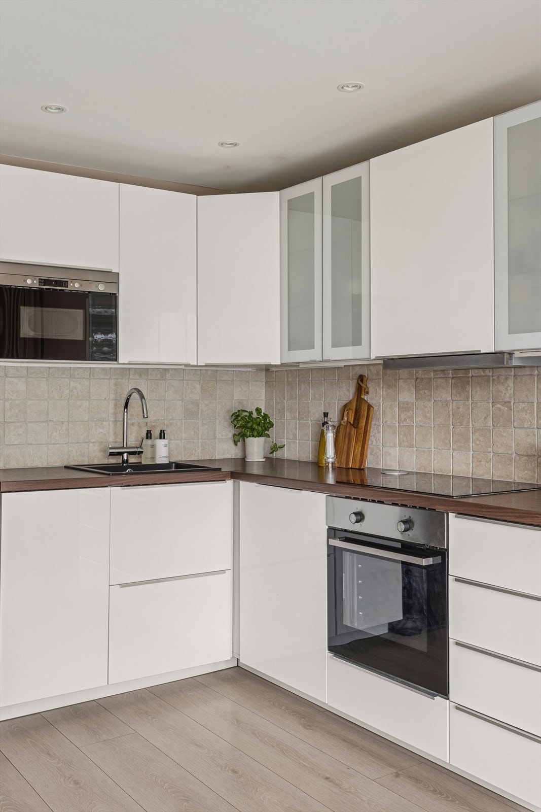 Et lyst kjøkken med kjøkkeninnredning med glatte fronter, laminat benkeplate med nedfelt vaskekum. Galleribilde