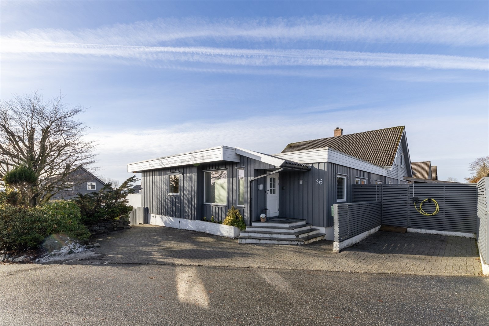 Ved inngangspartiet finner du et ryddig og stilrent område med belegningsstein, samt en trapp som leder opp til inngangsdøren. Her er det også parkering med plass til to biler - inkludert installert elbillader for enkel og moderne hverdagslogistikk. Galleribilde