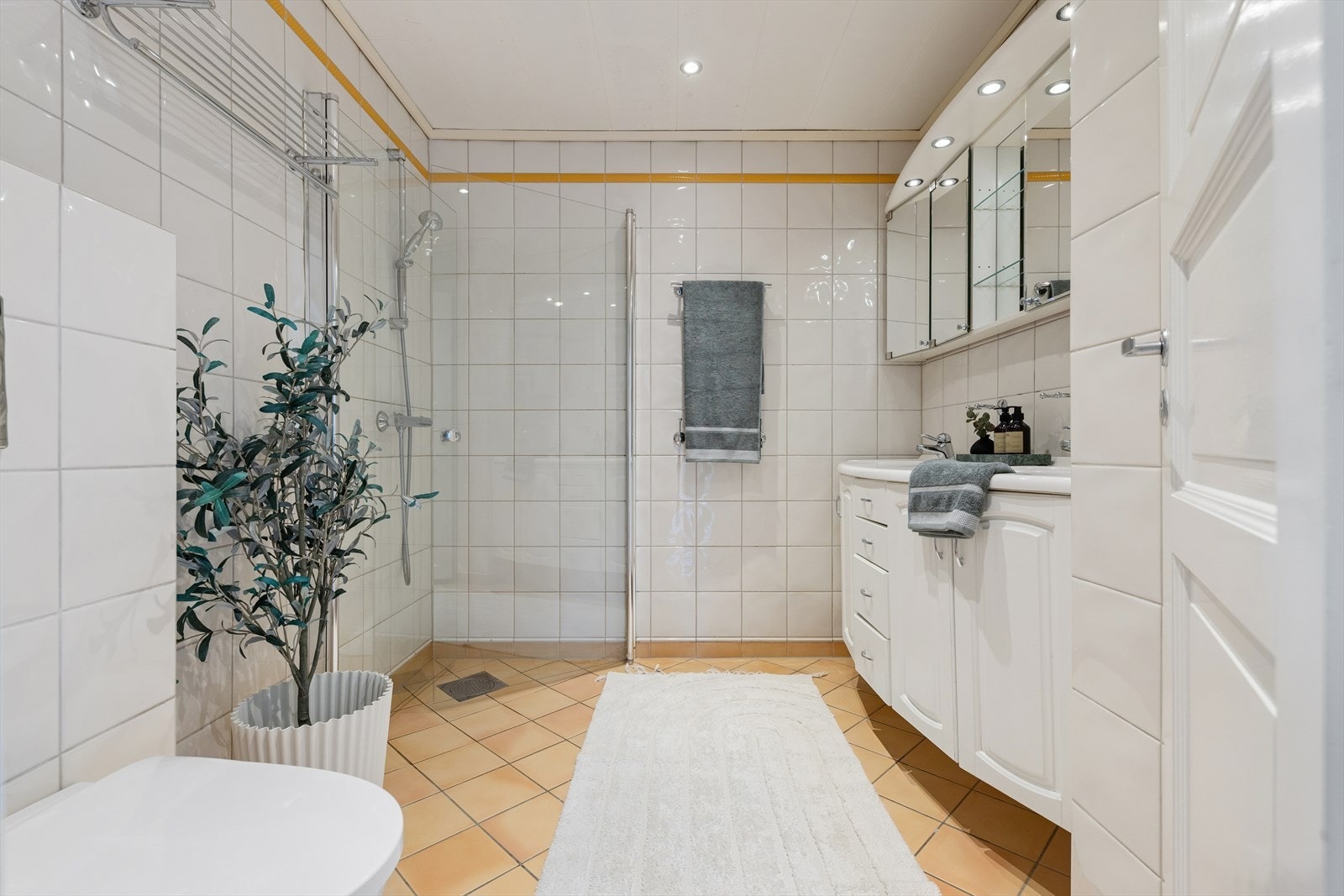 Badet i første etasje er helfliset og vannbåren varme som sikrer en behagelig temperatur året rundt. Innredet med doble nedfelte servanter, vegghengt toalett og et dusjhjørne med dusjvegger. Galleribilde