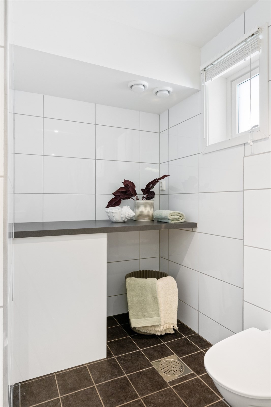 Rommet er innredet med dusjvegger, vegghengt toalett, baderomsinnredning med servant og opplegg for vaskemaskin. Galleribilde