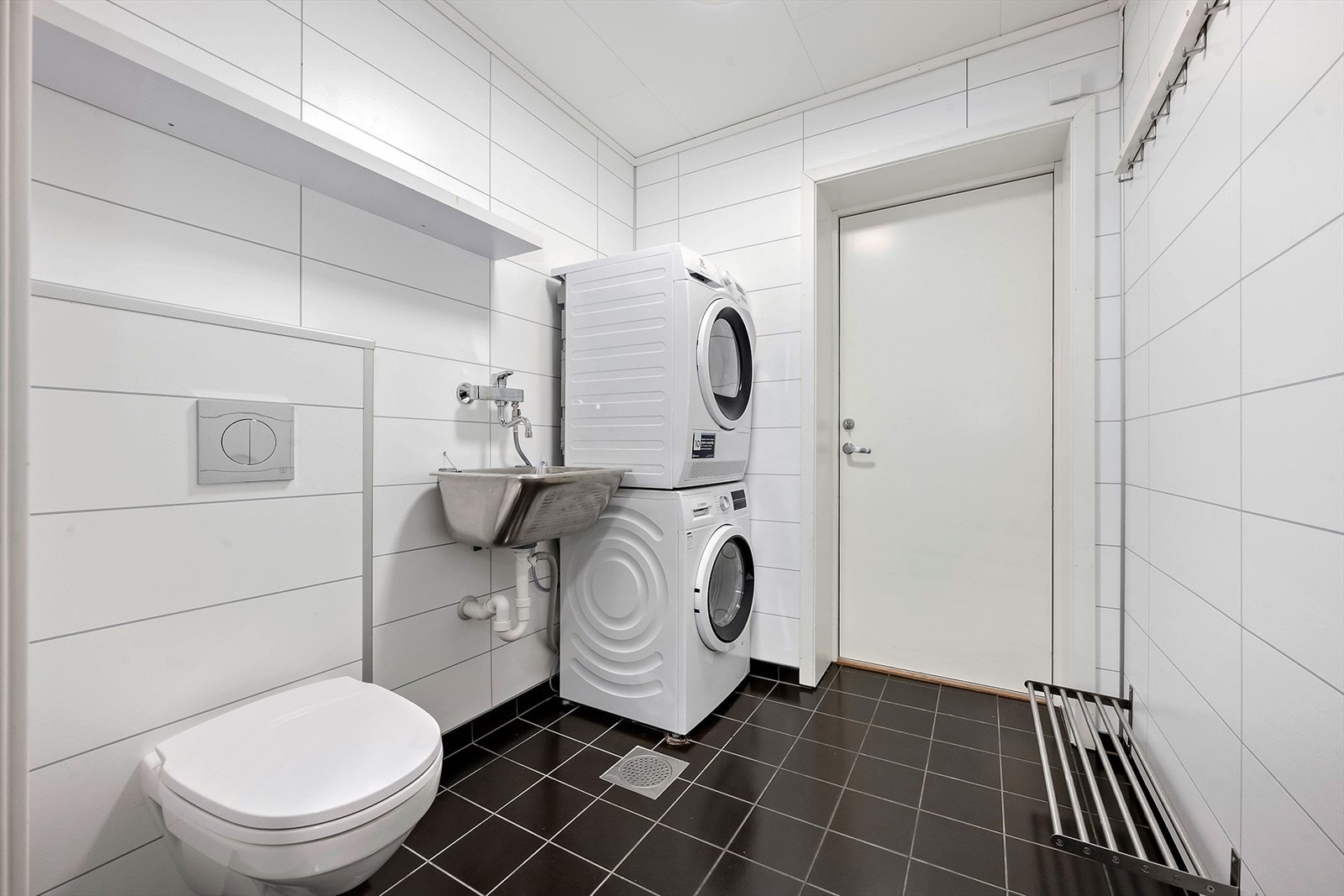 Vaskerommet i underetasjen flislagt gulv med varmekabler, samt at det er innredet med vegghengt toalett, utslagsvask og opplegg for vaskemaskin. Her er det også skyvedør mot gang i bolig og ytterdør ut til bod og garasje. Galleribilde