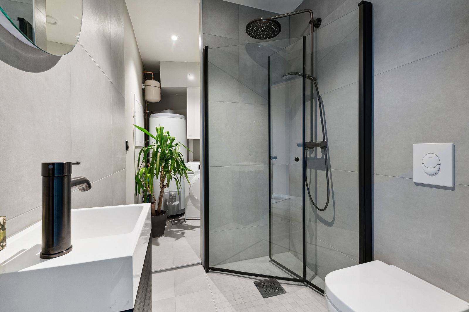 Bad nummer to er delvis delt med en vegg og inneholder veggmontert toalett, servantinnredning og dusjhjørne med glassdører. Galleribilde