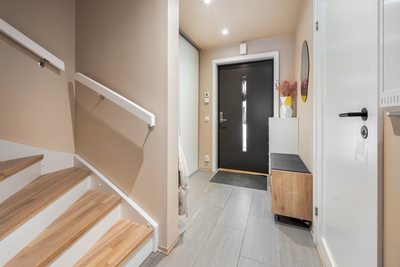 Fra entréen leder en lakkert tretrapp opp til boligens andre etasje. Galleribilde