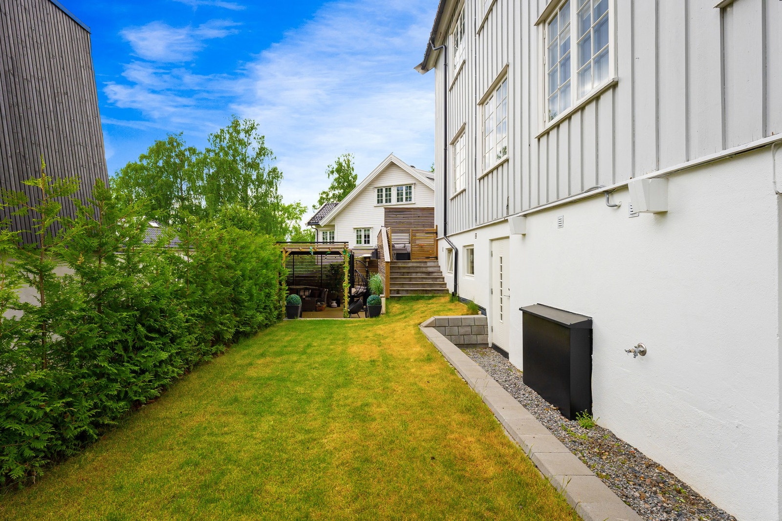 Eiendommen er pent opparbeidet med gressplener, bed, busker og hekker Galleribilde