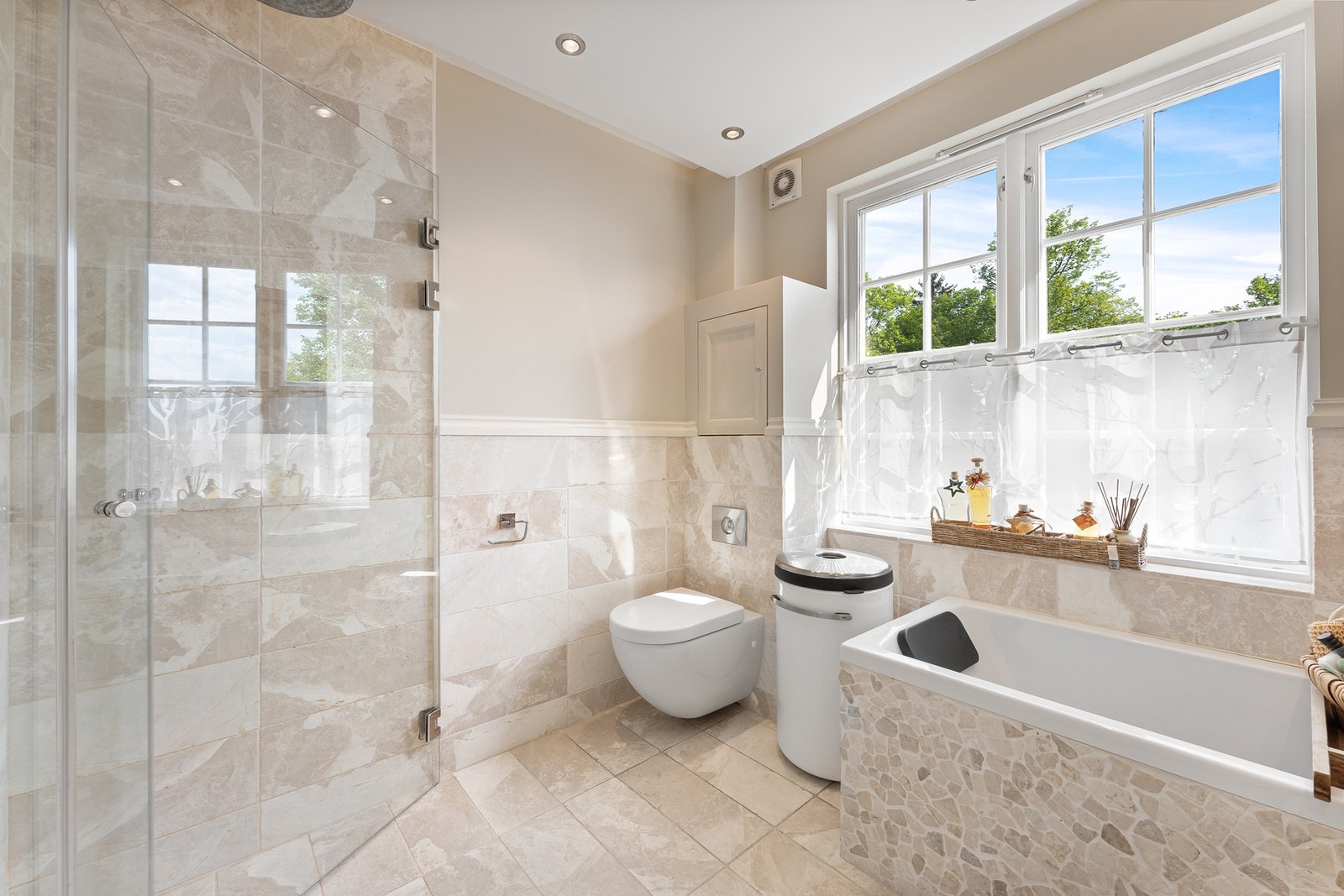 Badekar med mosaikkfliser og dusjhjørne med foldedører i herdet glass, innebygget såperom i vegg, rennesluk langs veggen og innebygget dusjarmatur med regnfallsdusj Galleribilde