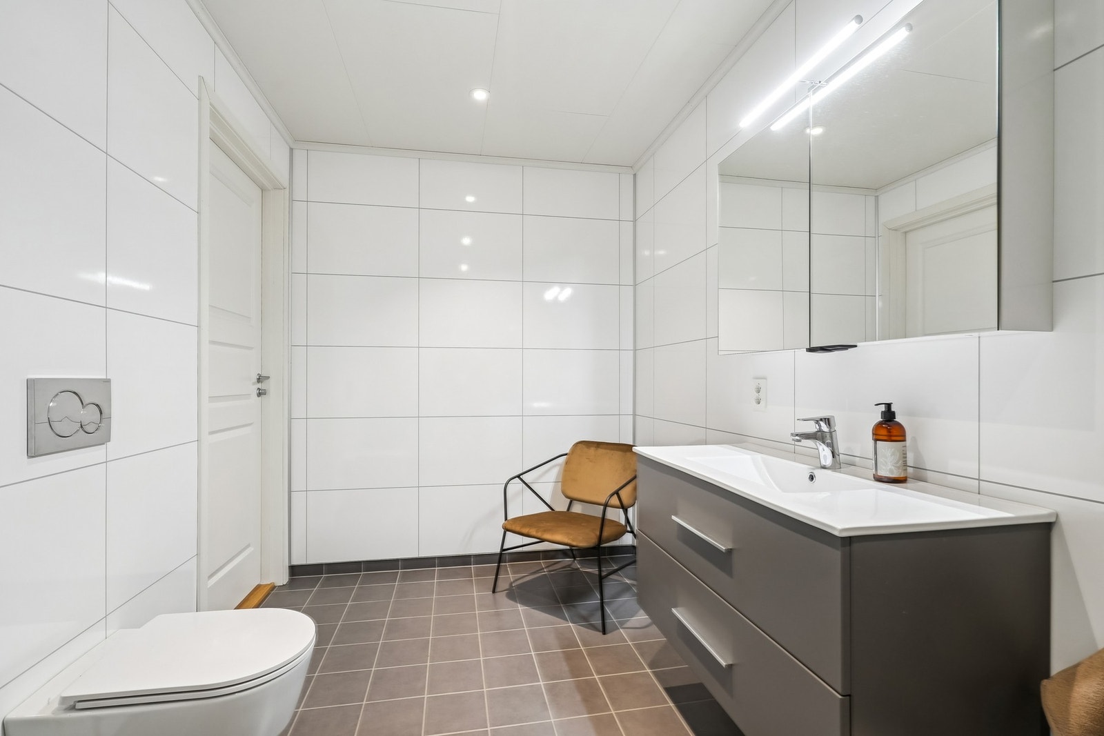 Pen innredning med glatte skuffefronter og helstøpt servant over. Skapspeil med belysning over. Galleribilde