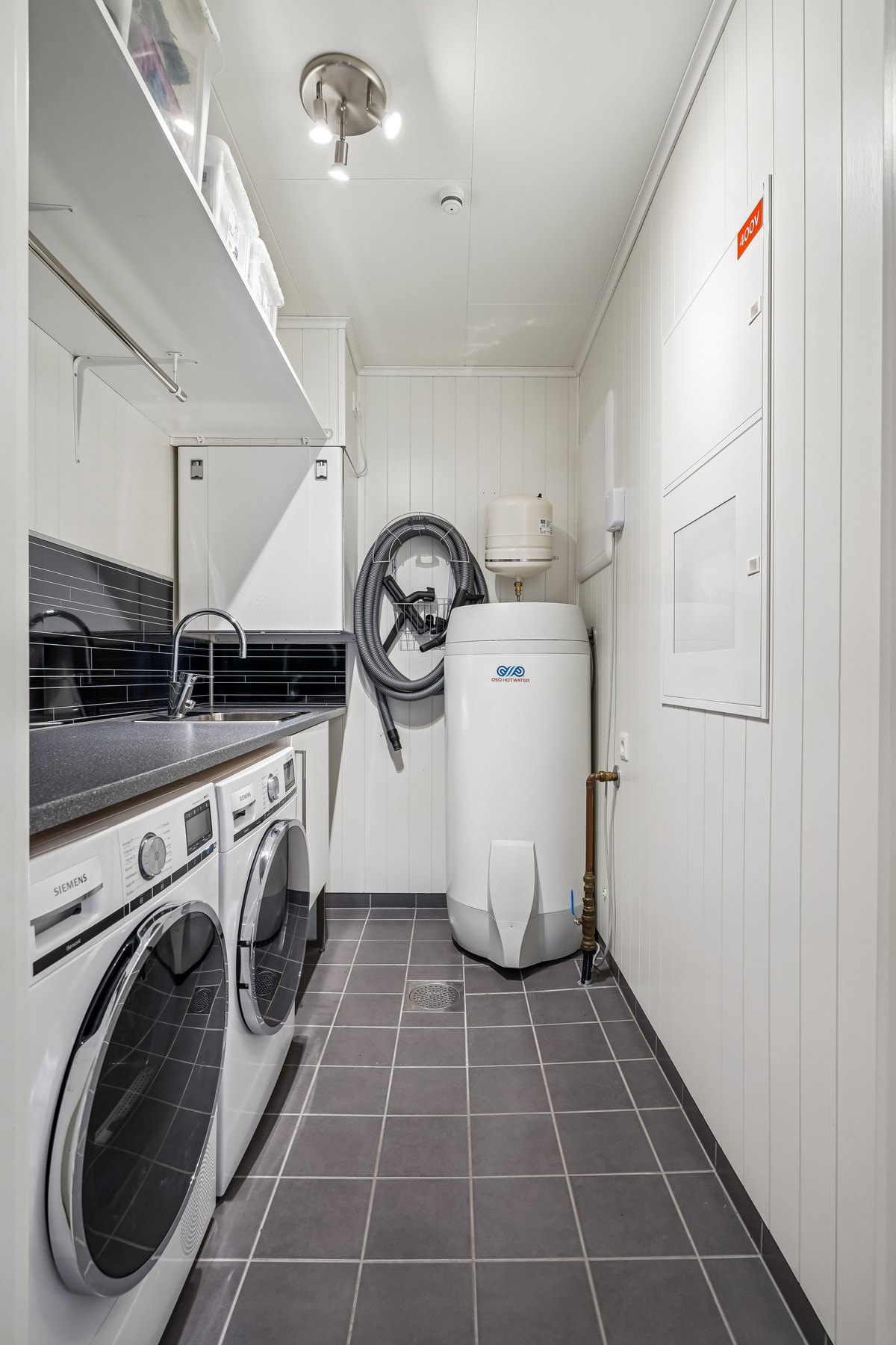 Vaskerom med flislagt gulv. Praktisk innredning og opplegg for vaskemaskin. Rommet er betegnet som teknisk bod på godkjente byggetegninger. Galleribilde