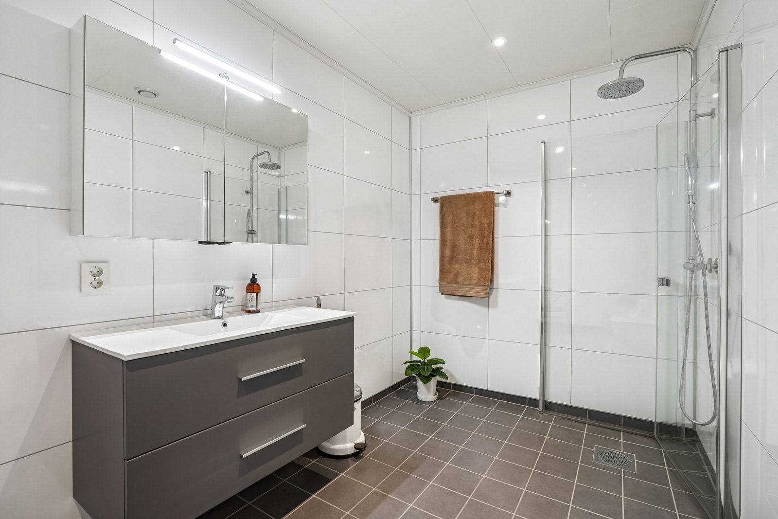 Badet er utstyrt med vegghengt toalett og dusjhjørne med innfellbare dusjdører i glass. Galleribilde