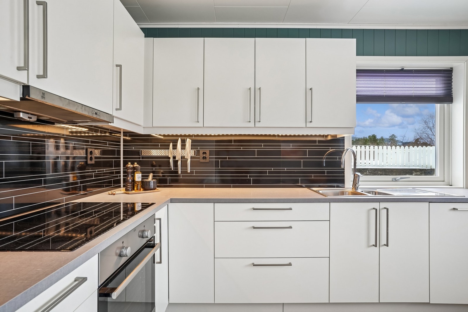 Det er montert vannbestandige plater på veggen under overskap med belysning. Galleribilde