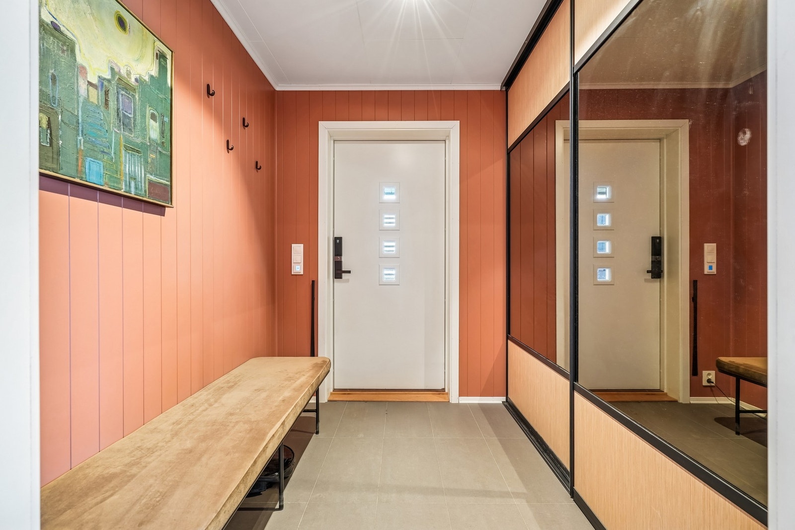 Entréen har flislagt gulv med elektriske varmekabler. Her er det plass til sittebenk om ønsket og praktisk skyvedørsgarderobe Galleribilde